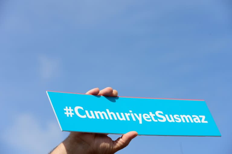 A protestors holds a sign with the hashtag, "Cumhuriyet will not be silent"