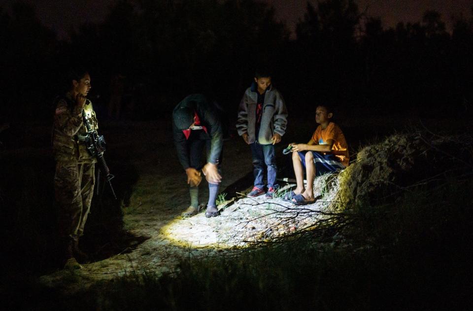 A National Guardswoman speaks to three unaccompanied children who had just arrived on the banks of the Rio Grande after crossing the U.S.-Mexico border on a raft into the United States in Roma, Texas, on July 9, 2021.  / Credit: Paul Ratje/AFP via Getty Images