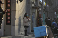 A woman wearing a mask to protect herself from the coronavirus stands along a street in Wuhan in central China's Hubei province on Thursday, Jan. 14, 2021. A global team of researchers for the World Health Organization arrived Thursday in the Chinese city where the coronavirus pandemic was first detected to conduct a politically sensitive investigation into its origins amid uncertainty about whether Beijing might try to prevent embarrassing discoveries. (AP Photo/Ng Han Guan)