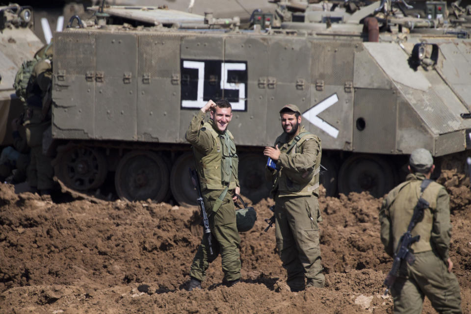 Israeli soldiers react as they work on their vehicles at a gathering area near the Israel-Gaza border, in southern Israel, Tuesday, March 26, 2019. Israeli Prime Minister Benjamin Netanyahu returned home from Washington on Tuesday, heading straight into military consultations after a night of heavy fire as Israeli aircraft bombed Gaza targets and the strip's militants fired rockets into Israel. (AP Photo/Ariel Schalit)