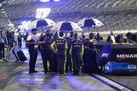 Drivers and crew members seek shelter under umbrellas as rain falls before the second of two qualifying NASCAR auto races for the Daytona 500 at Daytona International Speedway, Thursday, Feb. 11, 2021, in Daytona Beach, Fla. (AP Photo/John Raoux)