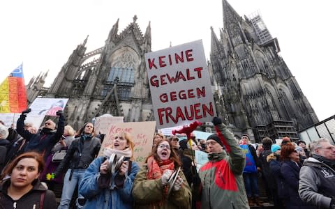 A man holds up a sign reading "No violence against women" as he takes part in a demonstration in front of the cathedral in Cologne - Credit: ROBERTO PFEIL/AFP