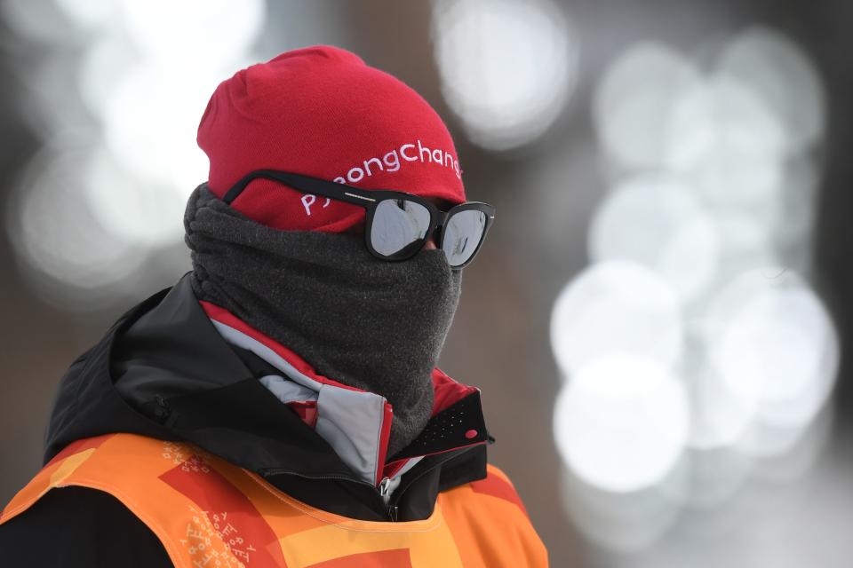 <p>An Olympic volunteer protects himself from the cold before the men’s 15km + 15km cross-country skiathlon at the Alpensia cross country ski centre during the Pyeongchang 2018 Winter Olympic Games on February 11, 2018 in Pyeongchang. / AFP PHOTO / Christof STACHE </p>