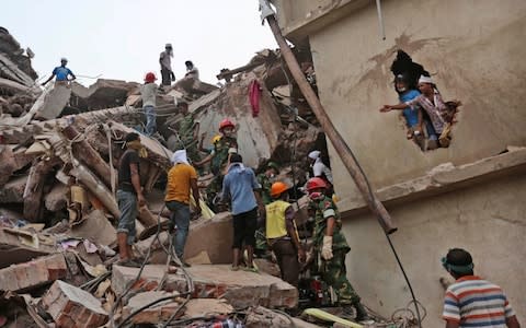 Bangladeshi rescue workers search for victims amid the rubble of a collapsed building in Savar, near Dhaka, Bangladesh - Credit: AP