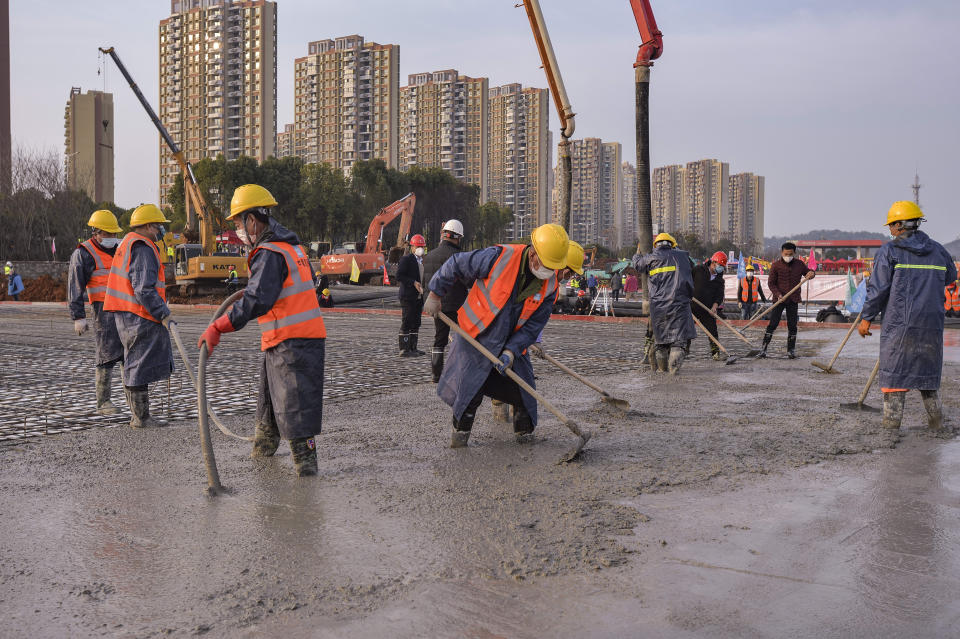 In this Tuesday, Jan. 28, 2020, photo, construction workers labor at the site of the Huoshenshan temporary field hospital being built in Wuhan in central China's Hubei Province. China as of Wednesday has more infections of a new virus than it did in with SARS, though the death toll is still lower. (Chinatopix via AP)