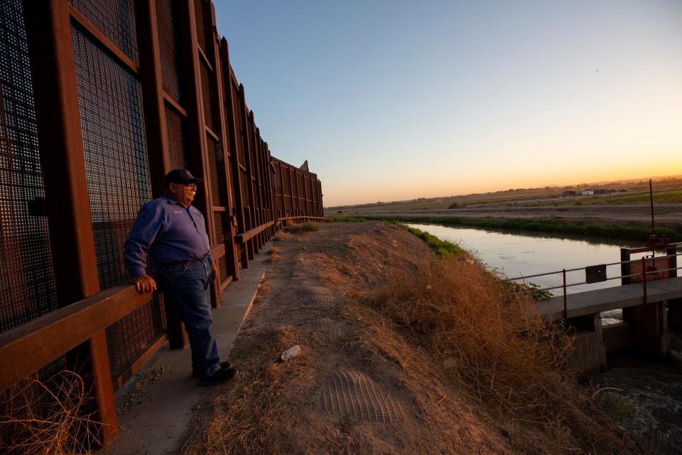 Robert Rios, water master for the El Paso County Water Improvement District No. 1 rests on the border wall during a sunrise in July 2023.