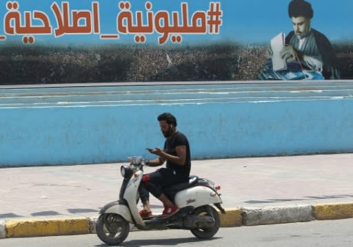 A man rides his scooter past a poster of Shiite cleric Moqtada Sadr in Sadr City, east of the Iraqi capital, on May 14, 2018