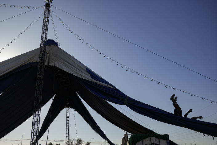 Bastian Rubio slides down a portion of the Timoteo Circus tent, during the dismantling of the tent for a move to another city, on the outskirts of Santiago, Chile, Tuesday, Dec. 20, 2022. An adopted grandson of founder René Valdés, Rubio is in charge of washing the circus tent, as well as setting it up and taking it down and performs as a musician, juggler, tightrope walker and clown. (AP Photo/Esteban Felix)