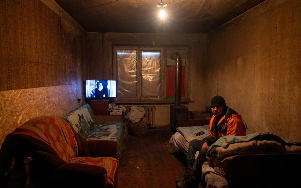 Viktor Ivanovich, 35, tries to keep warm in his apartment