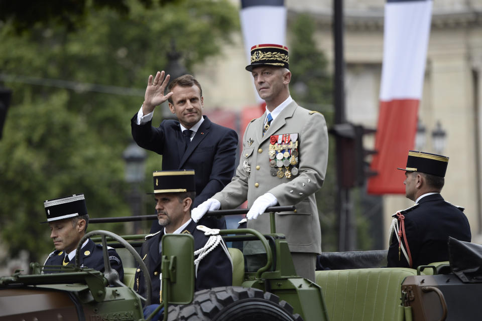 France's President Emmanuel Macron gestures in his command car next to French Armies Chief Staff General Francois Lecointre as they review troops before the start of the Bastille Day military parade down the Champs-Elysees avenue in Paris Sunday, July 14, 2019. French President Emmanuel Macron has overseen France's annual Bastille Day celebration, which this year showcased European defense cooperation. ( Eliot Blondet/POOL via AP)