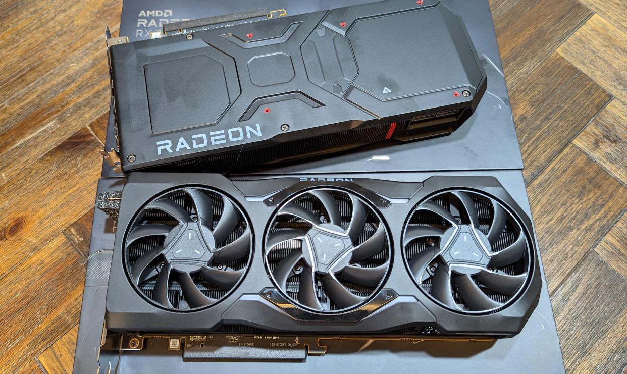 A picture of 2 black AMD Radeon RX 7900 XTX with its packaging on a brown wooden table