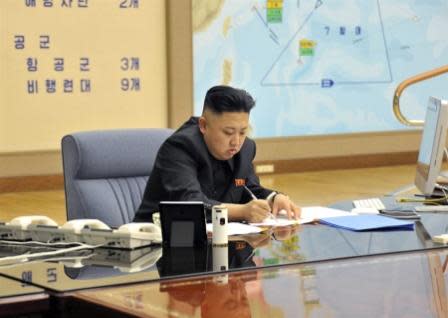 March 29, 2013. Kim Jong Un threatens missile strikes against US military bases on Okinawa and Guam, both marked by flags on the map visible in the image. Photo by the North Korean Central News Agency.