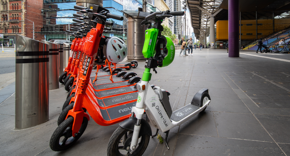 A row of e-scooters parked outside a train station in Melbourne. 