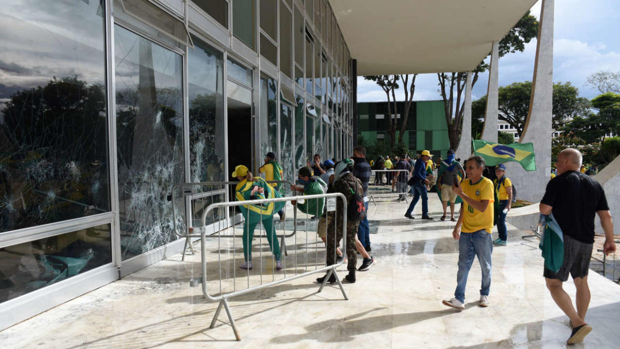 Supporters of Brazilian former President Jair Bolsonaro destroy a window of the the plenary of the Supreme Court in Brasilia on January 8, 2023. - Hundreds of supporters of Brazil's far-right ex-president Jair Bolsonaro broke through police barricades and stormed into Congress, the presidential palace and the Supreme Court Sunday, in a dramatic protest against President Luiz Inacio Lula da Silva's inauguration last week. (Photo by Ton MOLINA / AFP)