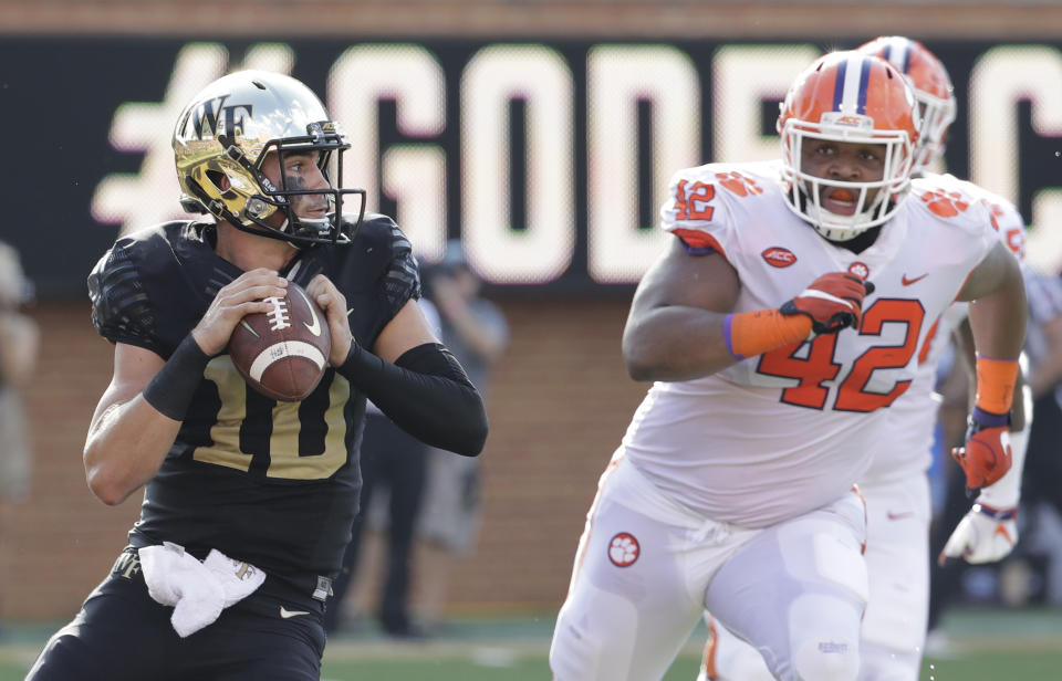 File-This Oct. 6, 2018, file photo shows Wake Forest's Sam Hartman (10) looking to pass under pressure from Clemson's Christian Wilkins (42) during the first half of an NCAA college football game in Charlotte, N.C. Wilkins is here to put a smile on your face, whether you like it or not. For four seasons, Wilkins has been bringing the jokes, zingers and sneaky pinches on the bottom at Clemson. The 300-pound All-America defensive tackle famously celebrated the Tigers’ 2016 national championship with a split and flashed a Heisman pose after a touchdown run this season. (AP Photo/Chuck Burton, File)