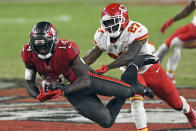 FILE - In this Sunday, Nov. 29, 2020 file photo, Tampa Bay Buccaneers wide receiver Chris Godwin (14) makes a diving catch in front of Kansas City Chiefs cornerback Rashad Fenton (27) during the second half of an NFL football game in Tampa, Fla. Applying franchise and even transition tags to players can have major ramifications on a team's present and future. That was never more of a consideration than this year, with the salary cap decreasing by, for now, $18 million. That's the first time the cap has gone down, which is due to lost revenues caused by the COVID-19 pandemic.(AP Photo/Jason Behnken, File)