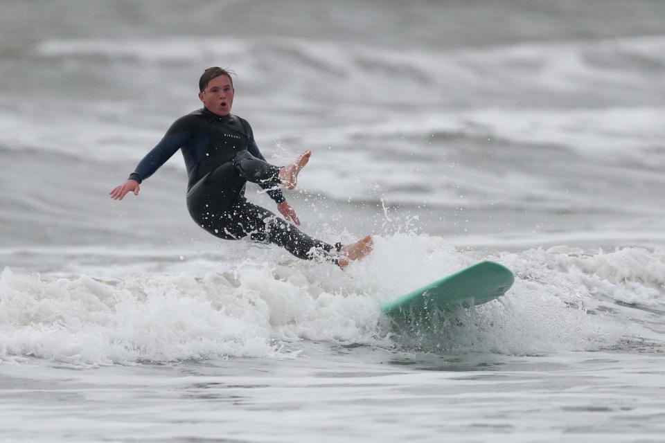 A surfer rides a wave in the sea at Bracklesham Bay in West Sussex (PA)