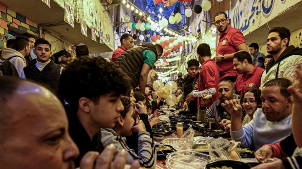 Egyptian Muslims gather in streets lined with long tables to break their fast together in a mass 