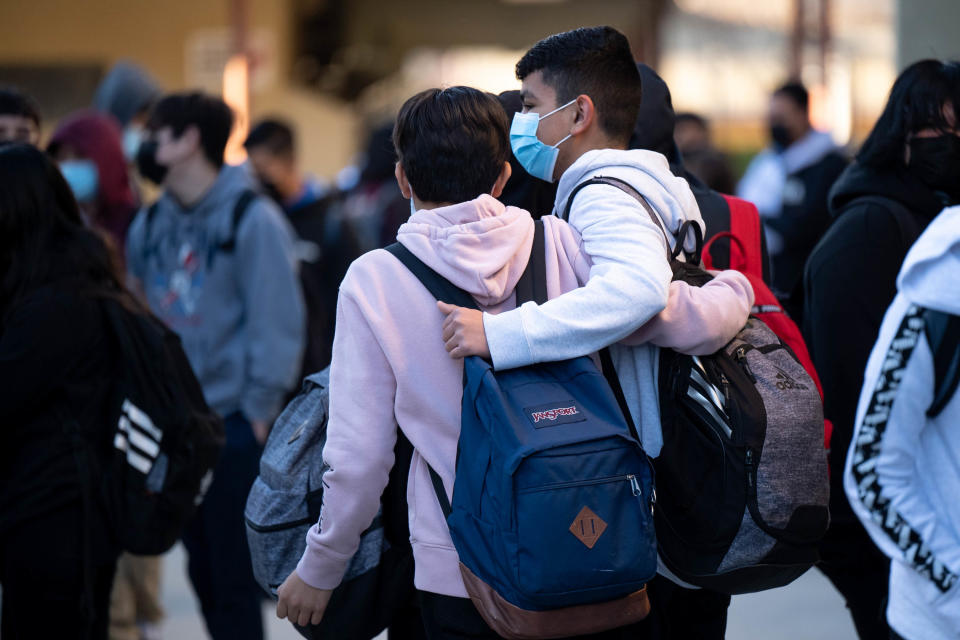 School kids holding each other and wearing masks