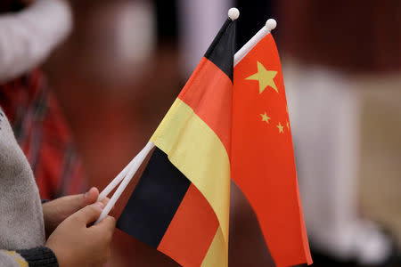 FILE PHOTO: A student holds flags of China and Germany before a welcome ceremony hosted by China's President Xi Jinping for German President Frank-Walter Steinmeier at the Great Hall of the People in Beijing, China December 10, 2018. REUTERS/Jason Lee/File Photo