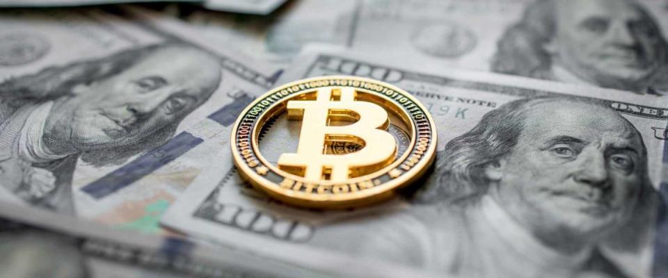 Golden symbolic coin Bitcoin on banknotes of one hundred dollars.