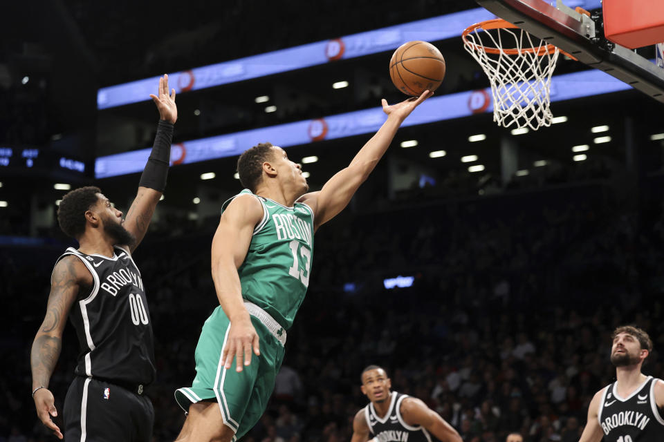 Boston Celtics guard Malcolm Brogdon (13) drives to the basket against Brooklyn Nets forward Royce O'Neale (00) as Nets forwards Joe Harris, right, and forward Nic Claxton, second from right, watch during the first half of an NBA basketball game, Sunday, Dec. 4, 2022, in New York. (AP Photo/Jessie Alcheh)