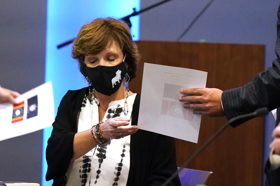 Mississippi State Flag Commission member Sherri Carr Bevis surrenders her ballot after voting for her flag choice during a meeting of the Mississippi State Flag Commission, Wednesday, Sept. 2, 2020, at the Two Mississippi Museums in Jackson, Miss. The magnolia centered banner was chosen by the nine-member committee and will go on the November ballot for voters consideration and if the majority votes yes, it will become the new state flag. (AP Photo/Rogelio V. Solis)