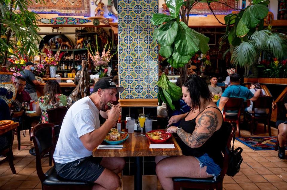 Brett Leach, 38, left, takes a bite of his food as he wife, Meghan Leach, 34, cuts into her meal at Tower Cafe on Sunday, July 18, 2021. After being closing for over a year, this weekend marks the restaurants first weekend back serving brunch after coronavirus related closures.