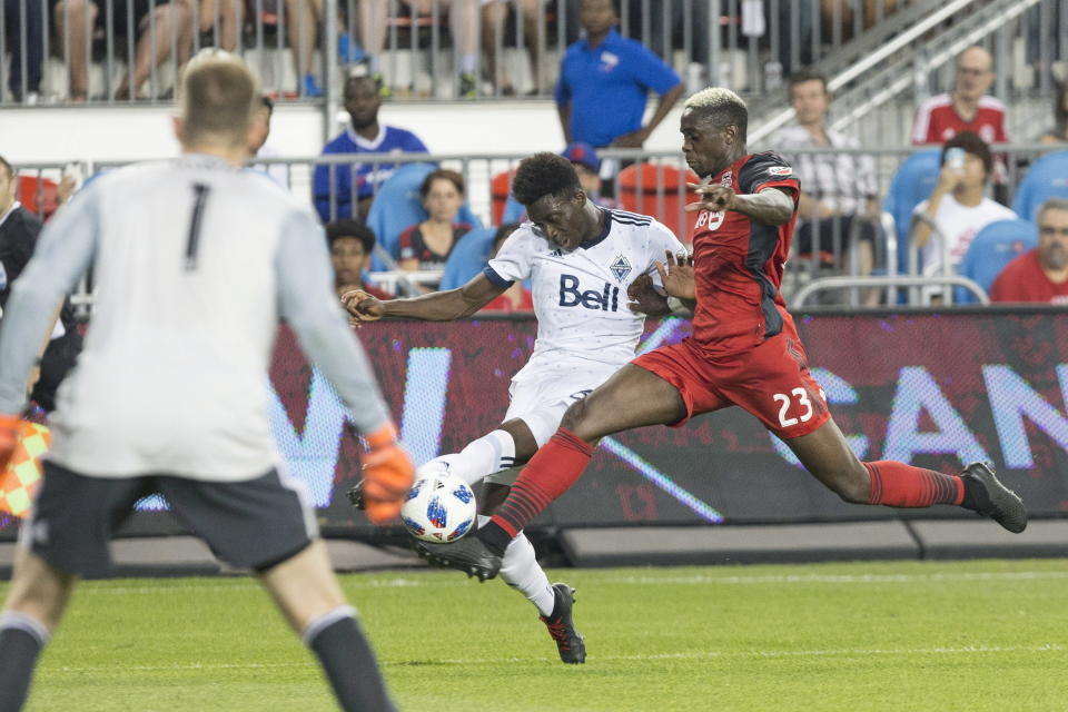 Vancouver Whitecaps' Alphonso Davies, center, tries to cross the ball past Toronto FC's Chris Mavinga during the first half in the second leg of the Canadian soccer championship final, Wednesday, Aug. 15, 2018, in Toronto. (Chris Young/The Canadian Press via AP)