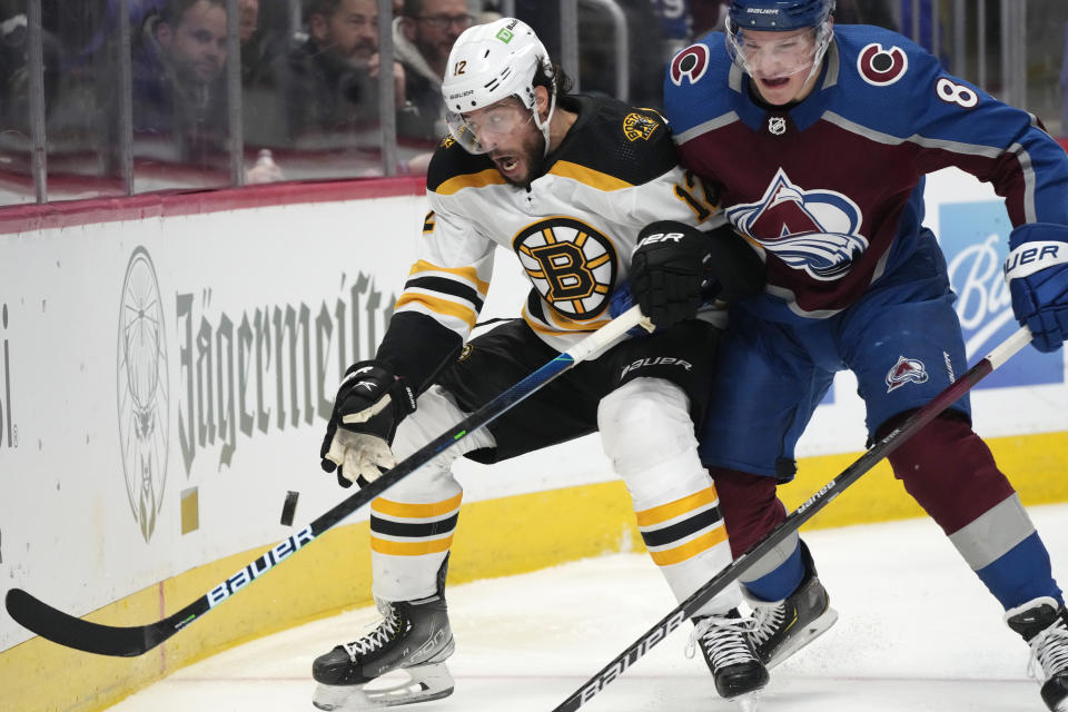 Colorado Avalanche defenseman Cale Makar, right, checks Boston Bruins center Craig Smith as he tries to control the puck in the second period of an NHL hockey game Wednesday, Jan. 26, 2022, in Denver. (AP Photo/David Zalubowski)