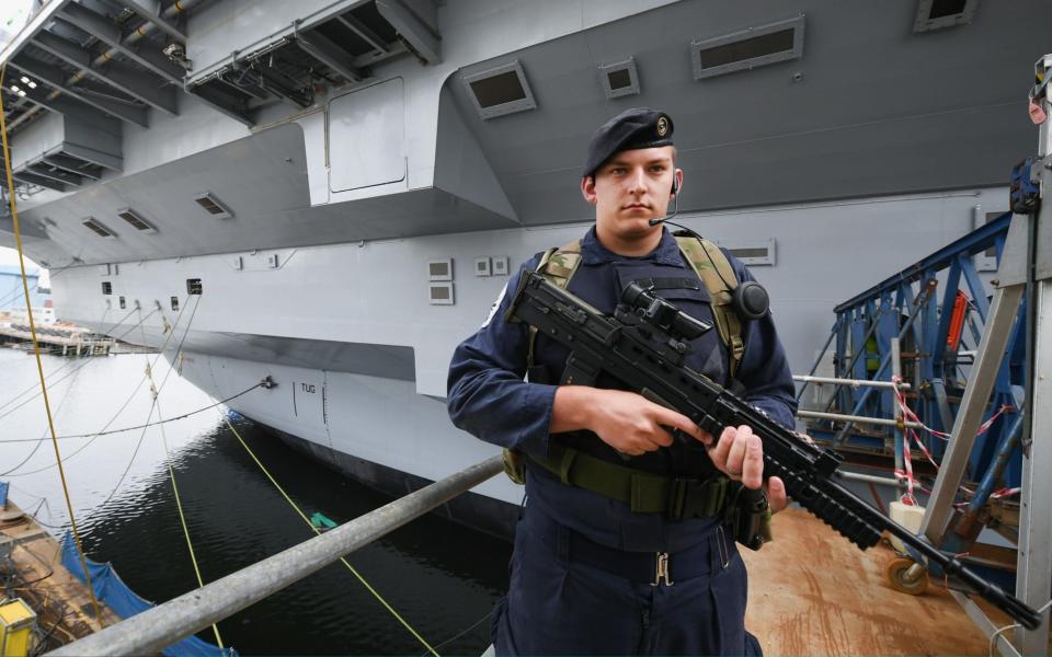 Bosuns mate Scott Campbell guards the Navy's new warship - Credit: Getty