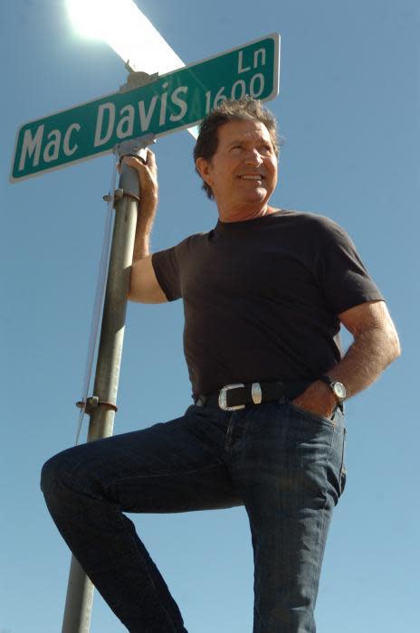 Mac Davis poses by a street sign for Mac Davis Lane in Lubbock. This year's annually anticipated Lubbock Lights event will be a tribute to the local legend who died in 2020.