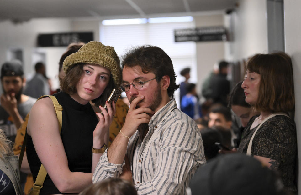 Emelyn Rutowski, 27, left, and Alessandro Uribe-Rheinbolt, 24, both of Hamtramck listen to the meeting in the hallway during the city council meeting at City Hall in Hamtramck, Mich., Tuesday, June 13, 2023. The big turnout by the public is for public comment on the flag neutrality law being considered by the city council. (Robin Buckson/Detroit News via AP)