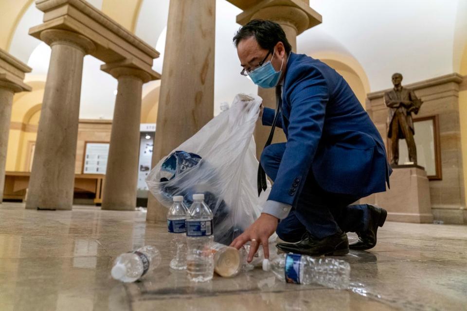 Rep Andy Kim, D-NJ, cleans up debris and trash on the morning of 7 Janurary, 2021, after rioters stormed the Capitol (Andrew Harnik, AP)