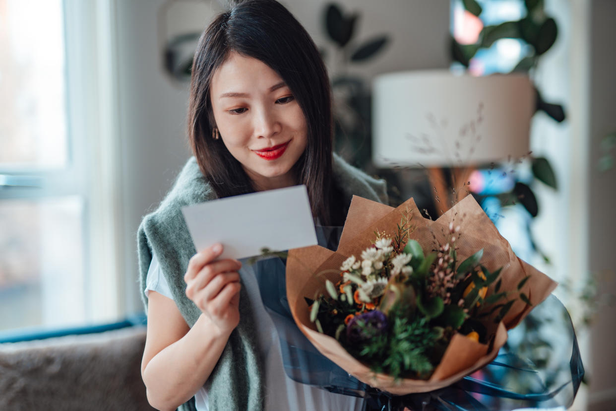 young asian woman holding bouquet of flowers and card for valentine's day