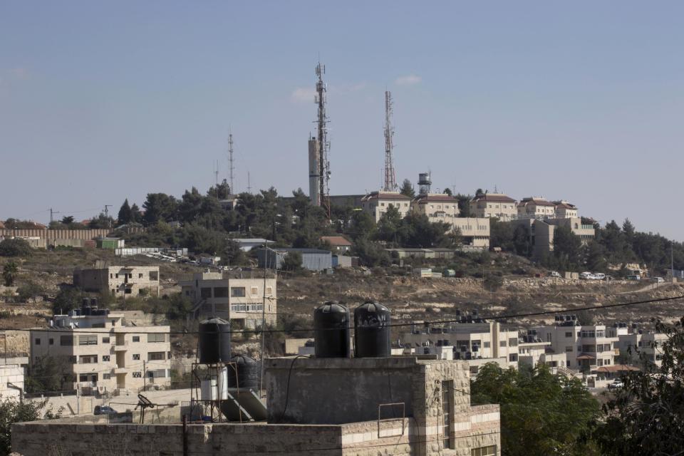 This Oct. 24, 2016, file photo shows part of the Israeli settlement of Psagot, background, overlooking Palestinian houses, in a suburb of the West Bank city of Ramallah. Israel says it has approved 2,500 homes in West Bank settlements In a statement from his office, Defense Minister Avigdor Lieberman says he and Prime Minister Benjamin Netanyahu agreed on the approval “in response to housing needs.” He says the majority of the housing units will be built in settlement blocs, areas where most settlers live and which Israel wants to keep under its control under any future peace deal with the Palestinians. (AP Photo/Nasser Nasser, File)