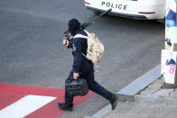 A Georgian police sniper carries his rifle on a position near a bank where an armed assailant took several people hostage in the town of Zugdidi in western Georgia, Wednesday, Oct. 21, 2020. An armed assailant took several people hostage at a bank in the ex-Soviet nation of Georgia on Wednesday, authorities said. The Georgian Interior Ministry didn't immediately say how many people have been taken hostage in the town of Zugdidi in western Georgia, or what demands the assailant has made. Police sealed off the area and launched an operation "to neutralize the assailant," the ministry said in a statement. (AP Photo/Zurab Tsertsvadze)