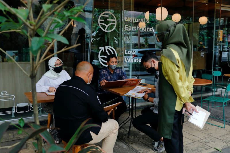 Customers talk with a worker while ordering some food at an outlet of Burgreens in Serpong