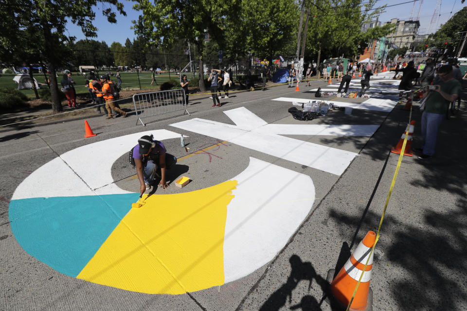 An artist paints one of the large letters that read "Black Lives Matter" on a street near Cal Anderson Park, Thursday, June 11, 2020, inside what is being called the "Capitol Hill Autonomous Zone" in Seattle. Following days of violent confrontations with protesters, police in Seattle have largely withdrawn from the neighborhood, and protesters have created a festival-like scene. (AP Photo/Ted S. Warren)