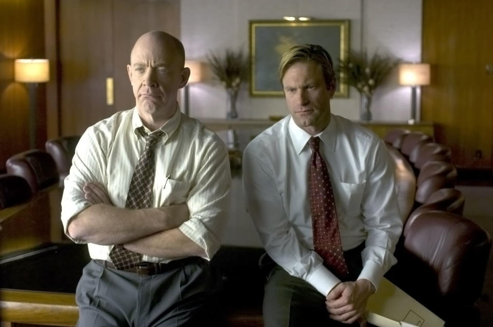 J.K. Simmons and Aaron Eckhart sit on a board room table