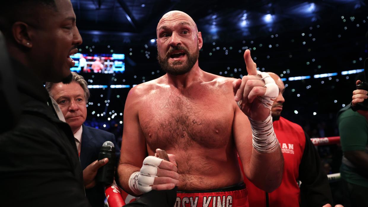  Tyson Fury, wearing red shorts emblazoned with 'Gypsy King', stands in a boxing ring pointing ahead of the Fury vs Usyk live stream  . 