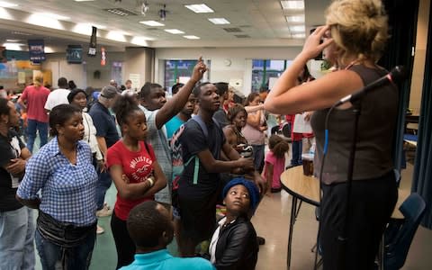 A Red Cross volunteer (R) gives out room assignments at a shelter within the Pizzo Elementary School in Tampa, Florida, - Credit: Jim Watson/AFP