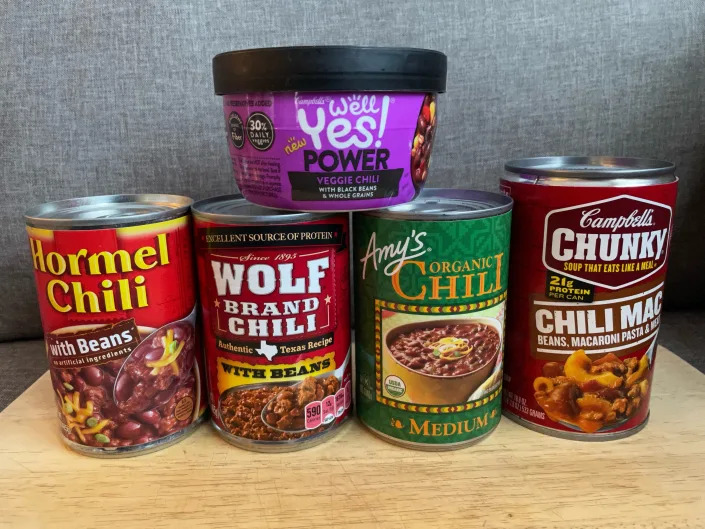 Cans of chili lined up in front of gray background