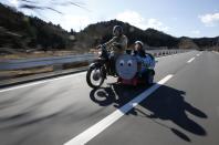 Sadao Kimbara (i) monta en una motocicleta Honda con sidecar hecho con un barril de petróleo, mientras su nieto Rui sonríe en Ome, a las afueras de Tokio.