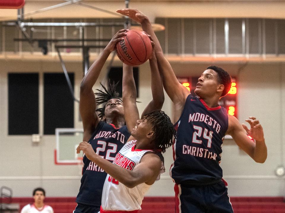 Lincoln's Beau Blackman, center, fights for a rebound with Modesto Christian's Myles  Clayton, left, and Jamari Phillips during a boys varsity basketball game at Lincoln High School  in Stockton. 