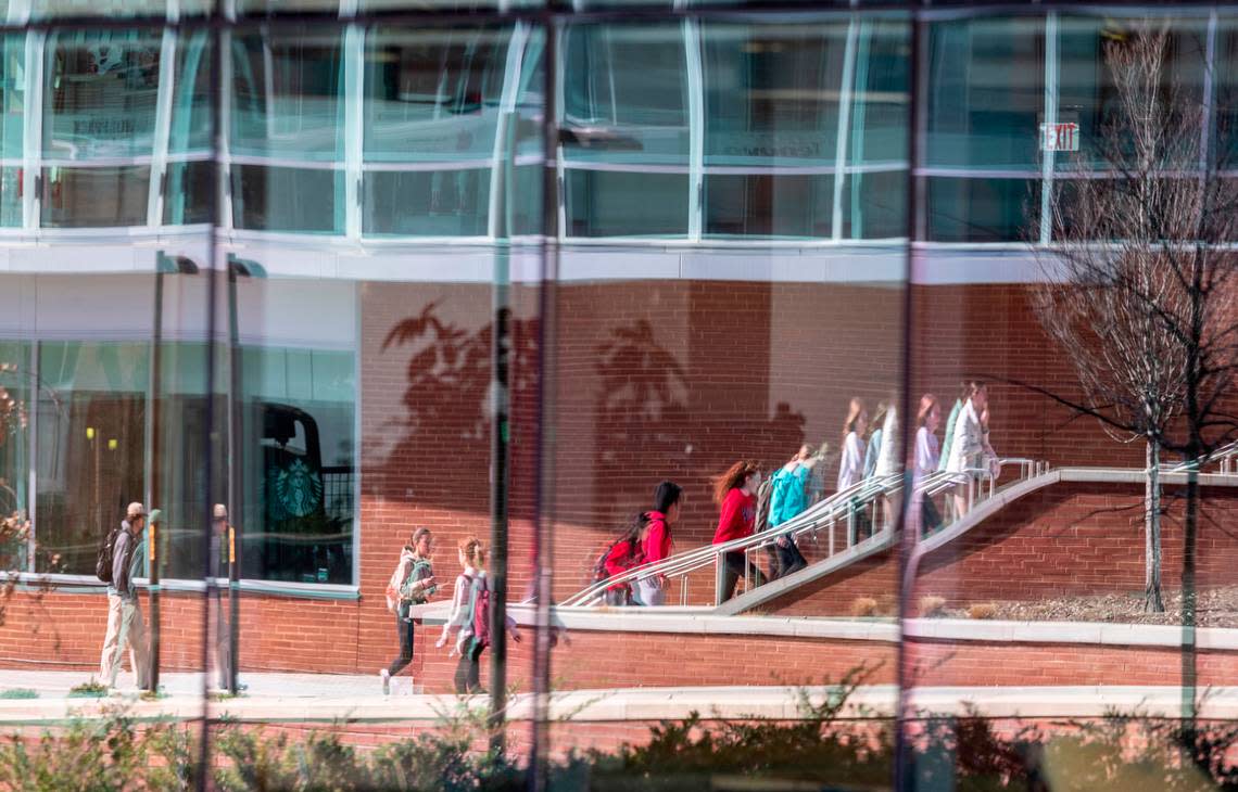 Students are reflected in glass outside the Talley Student Union at N.C. State’s main campus Monday, Feb. 13, 2022.