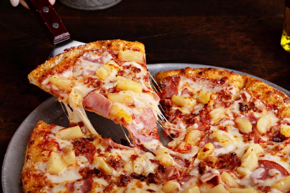 Hawaiian pizza with ham and pineapple cut into slices.