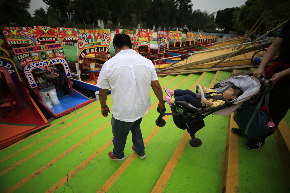 A worker helps a tourist couple carry their daughter in a stroller onto a trajinera, colorful passenger boats typically rented by tourists, families, and groups of young people, in Xochimilco, Mexico City, Friday, Sept. 6, 2019. The usually festive Nativitas pier was subdued and largely empty Friday afternoon, with some boat operators and vendors estimating that business was down by 80% on the first weekend following the drowning death of a youth that was captured on cellphone video and seen widely in Mexico. Borough officials stood on the pier to inform visitors of new regulations that went into effect Friday limiting the consumption of alcohol, prohibiting the use of speakers and instructing visitors to remain seated.(AP Photo/Rebecca Blackwell)