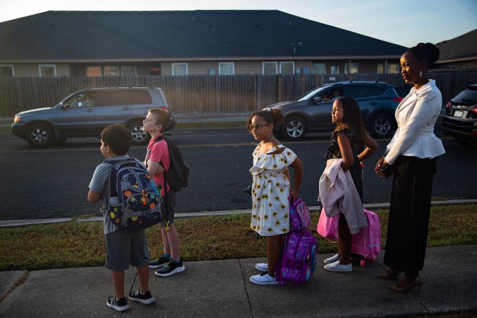 From left, Xavier Mondragon, 8; Joseph Andrews, 9; Ellaine Day, 8; Ellyse Day, 9; and Bascolyne Day wait for the bus to Windsor Park Elementary School on the first day of the 2022-23 school year in Corpus Christi on Aug. 9, 2022.