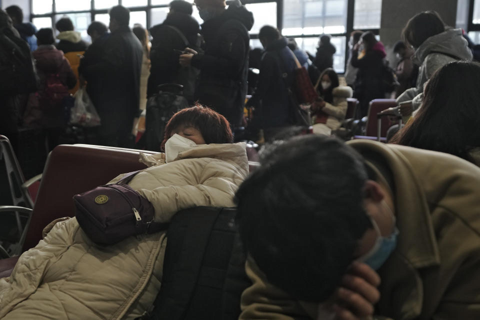 A woman wearing a face mask rests on a bench as travelers prepare to catch their trains at the West Railway Station in Beijing, Sunday, Jan. 15, 2023. The World Health Organization has appealed to China to keep releasing information about its wave of COVID-19 infections after the government announced nearly 60,000 deaths since early December following weeks of complaints it was failing to tell the world what was happening. (AP Photo/Andy Wong)